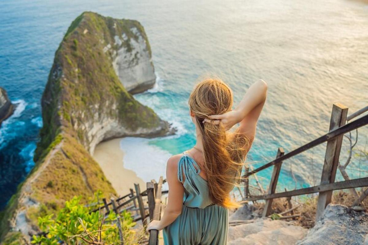 o femeie care stă pe o balustradă și privește oceanul