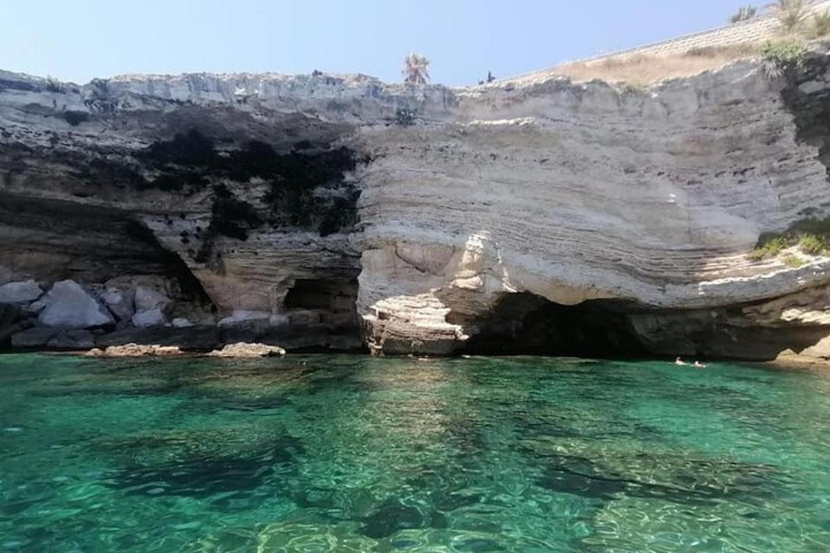 una grotta con acqua color smeraldo di fronte a una scogliera