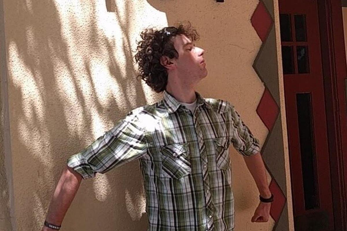 Un hombre con una camisa a cuadros de pie contra una pared