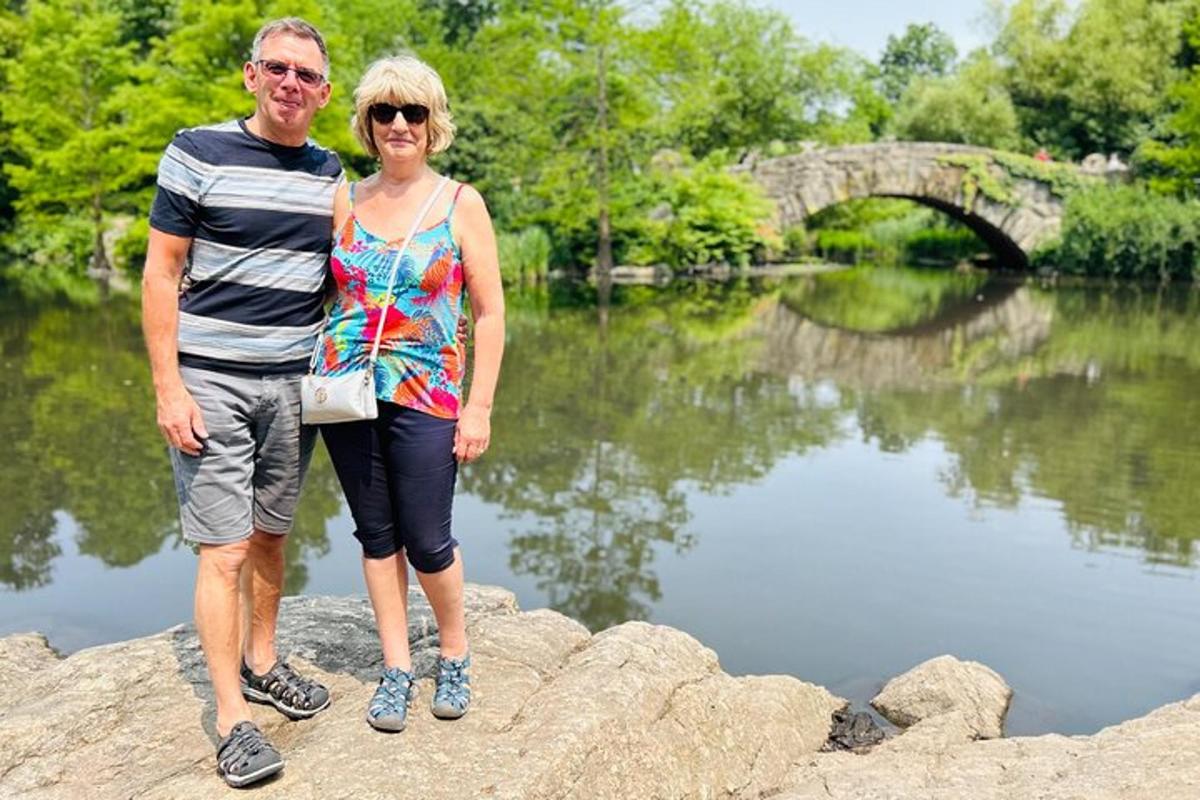 a man and a woman standing on rocks by a lake