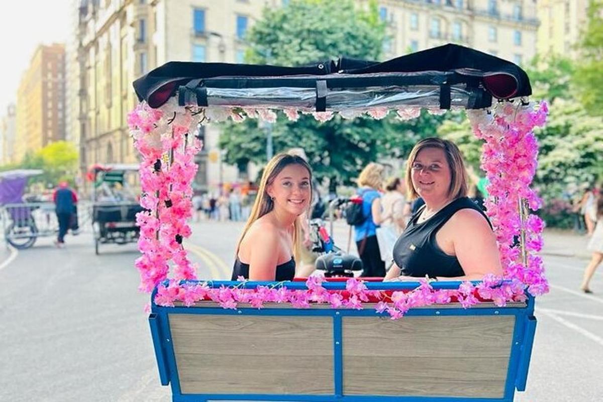 two women are riding a cart with pink flowers