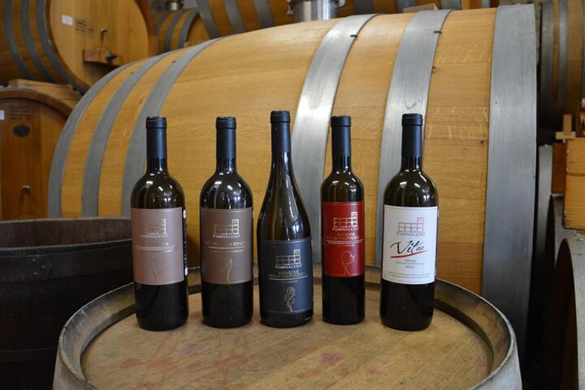 quattro bottiglie di vino appoggiate sopra una botte