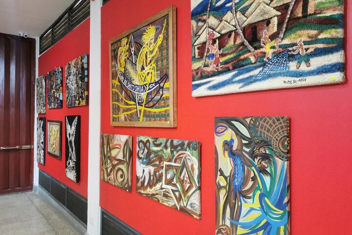 a wall full of paintings on a red wall