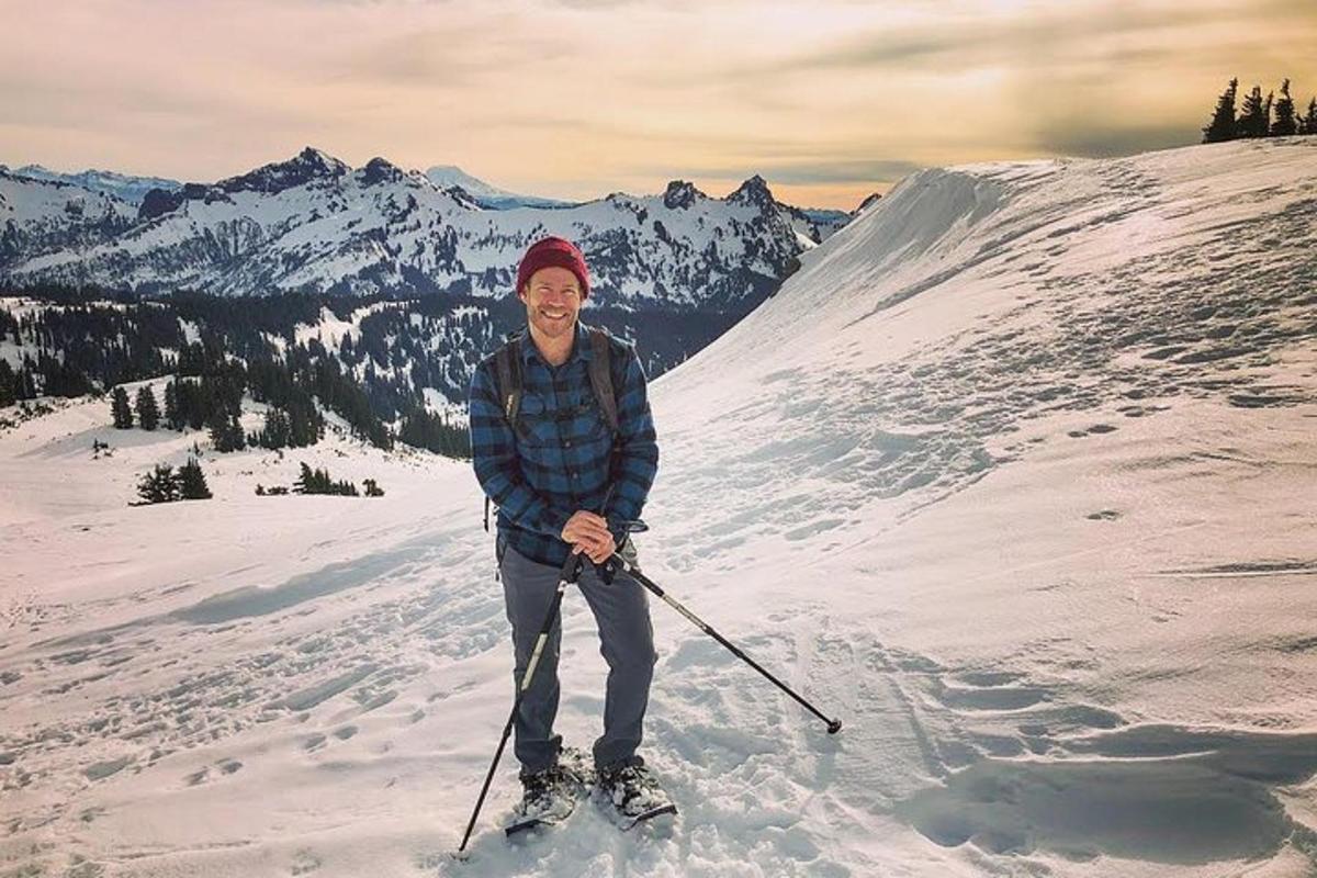 en man på skidor som står på ett snötäckt berg