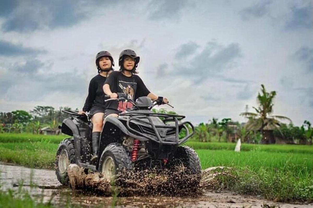 dua orang mengendarai kendaraan roda empat melewati lapangan berlumpur