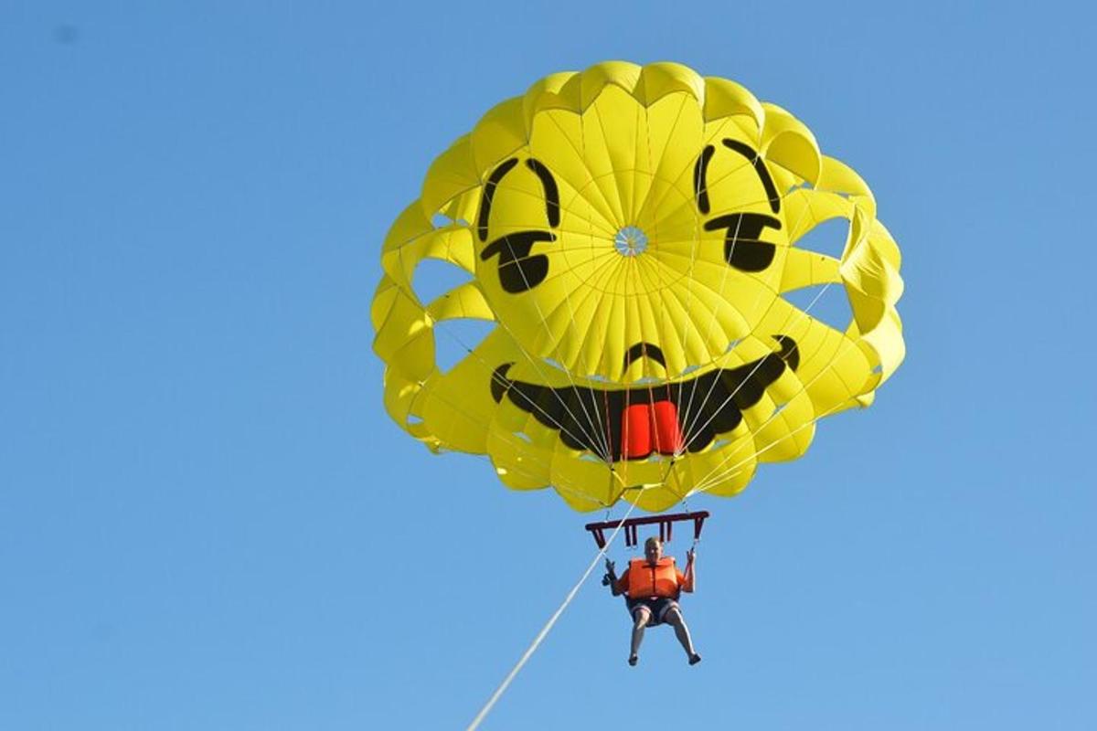 a man flying a yellow kite with a face on it