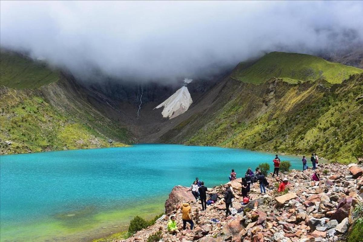 um grupo de pessoas em pé em uma montanha perto de um lago