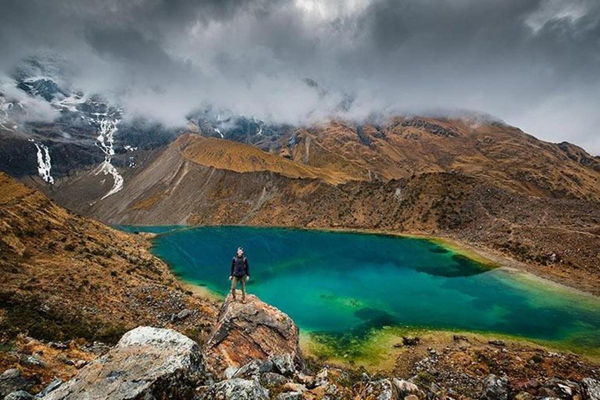 um homem em pé no topo de uma montanha com vista para um lago