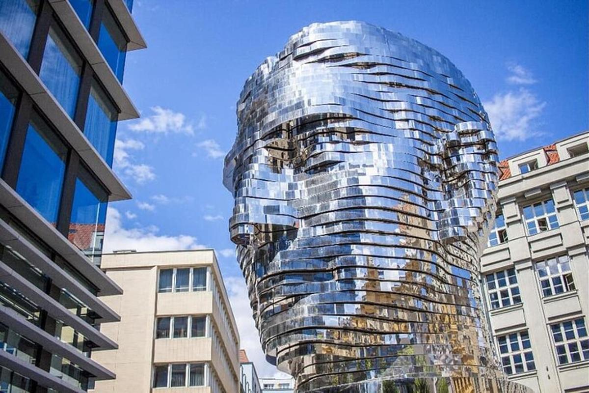 a large glass head statue in front of buildings
