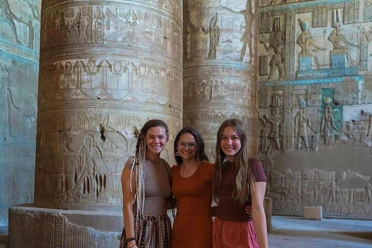 three women standing in front of a pillar with reliefs