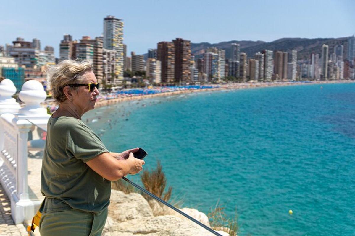 Un hombre parado en una cornisa con vista a una playa