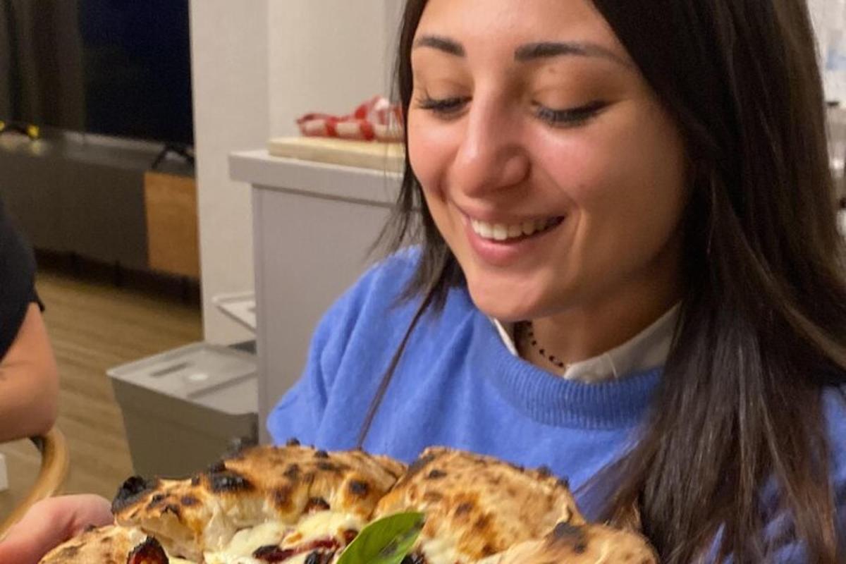 una donna sorride mentre guarda una pizza