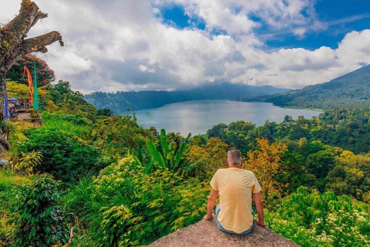 seorang lelaki duduk di atas batu melihat tasik
