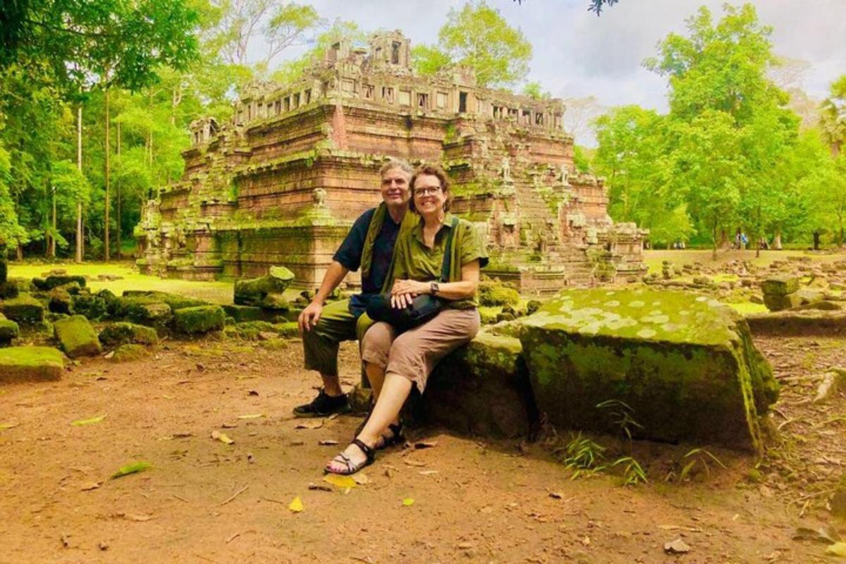 seorang lelaki dan wanita duduk di atas batu di hadapan sebuah bangunan