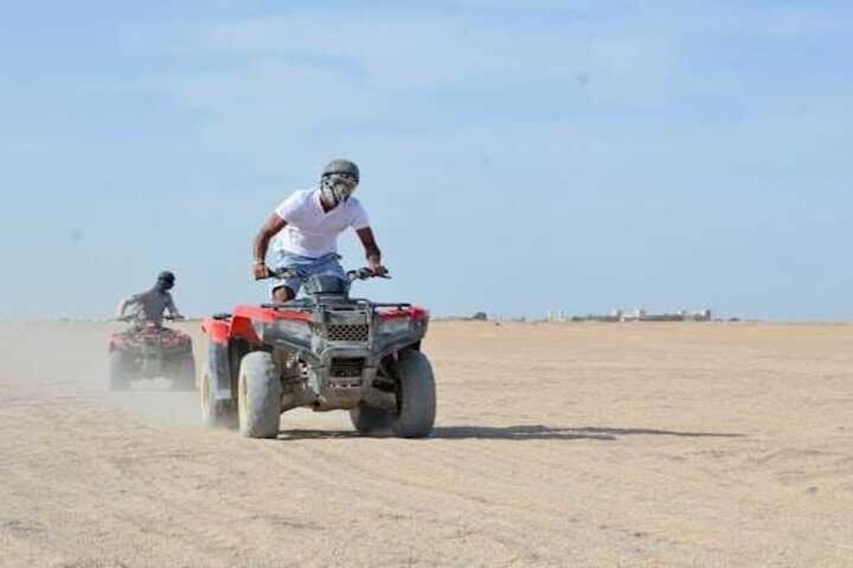 twee mensen rijden op quads in de woestijn