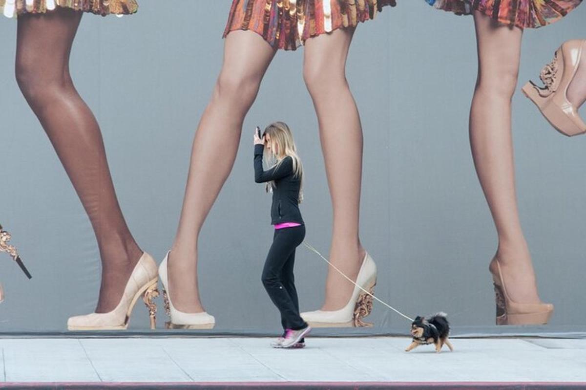 žena venčící psa na vodítku před modelkami