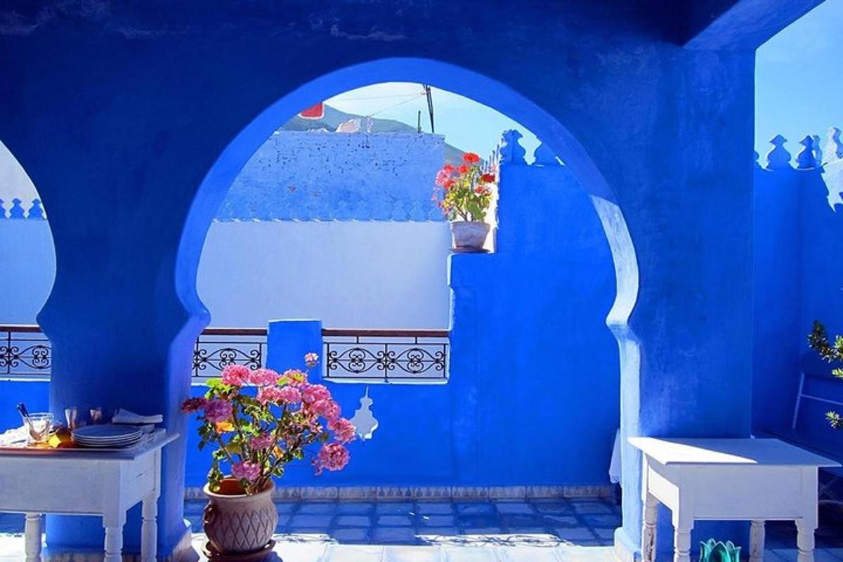 una parete blu con due tavoli e fiori in una stanza