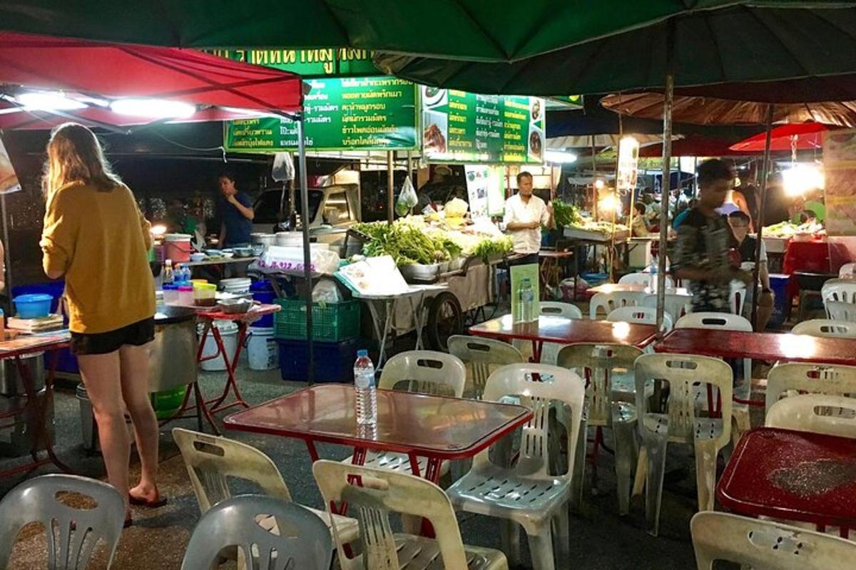 Una mujer parada en un mercado con mesas y sillas.
