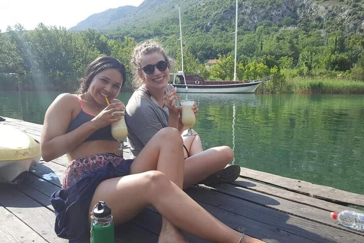 dvě mladé ženy sedící na molu s nápoji