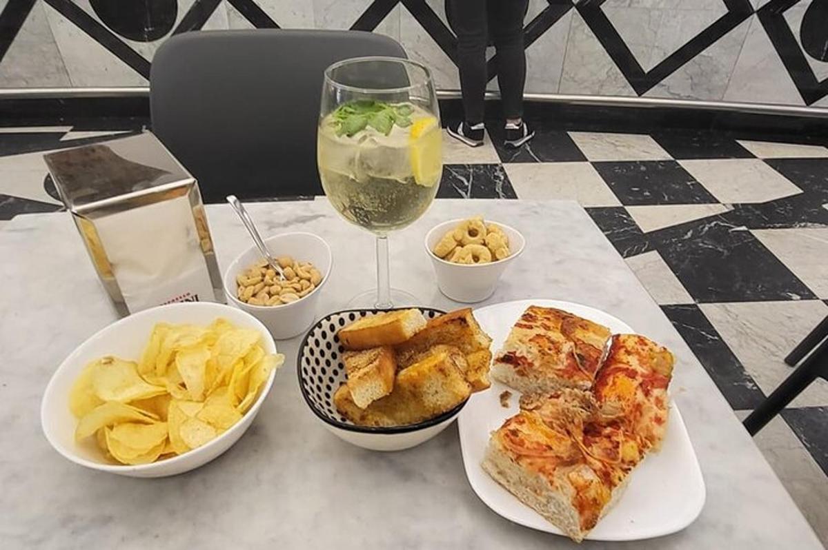 a table with plates of food and chips and a glass of wine