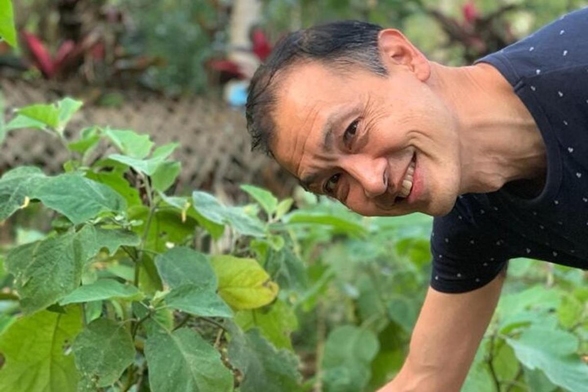 a man is smiling in front of some plants