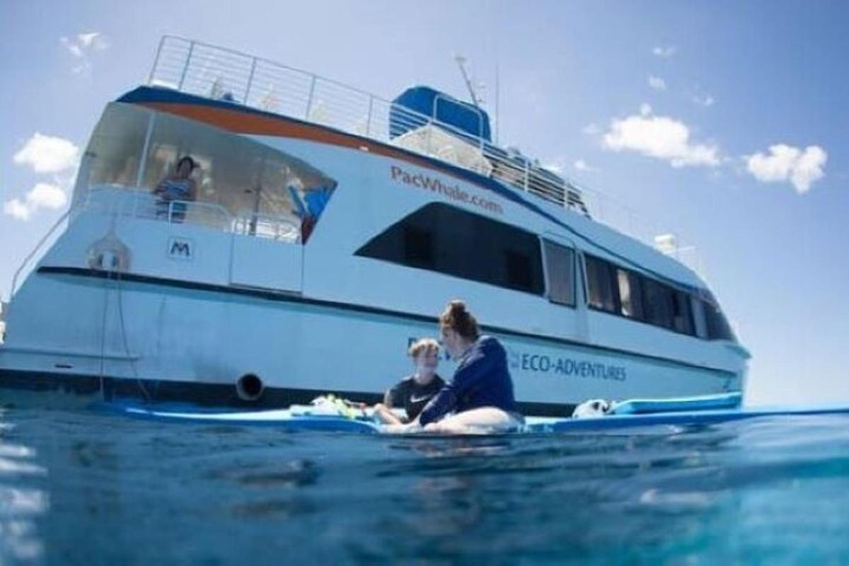 a woman and child sitting on the water in front of a boat