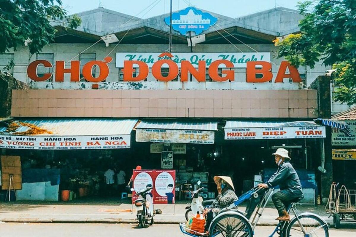 un home anant en bicicleta davant d'una botiga