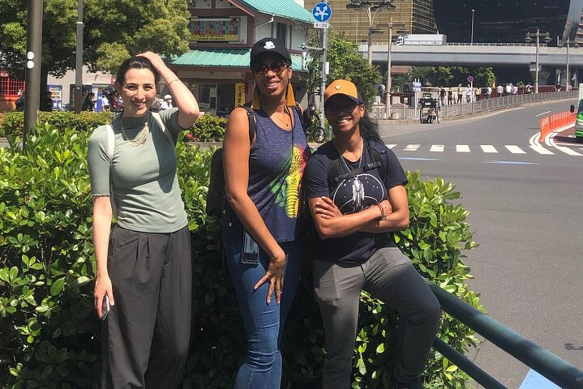 a group of three women standing next to a street