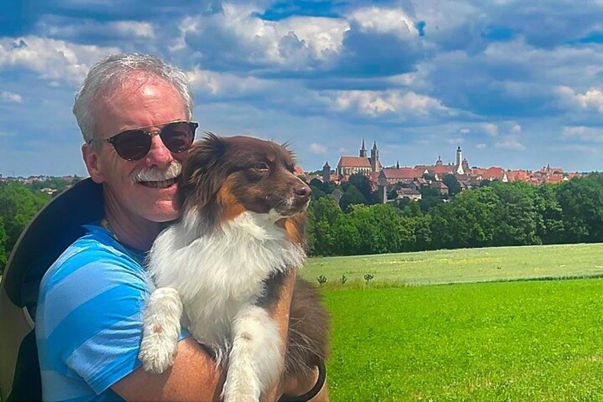ein Mann, der einen braun-weißen Hund auf einem Feld hält