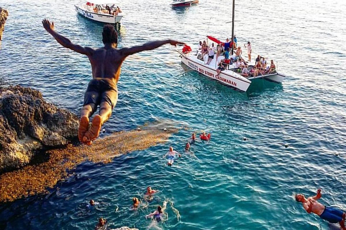 isang lalaking tumatalon mula sa isang bangin patungo sa tubig na may bangka