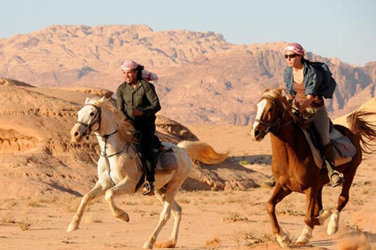 شخصان يركبان على الخيول في الصحراء
