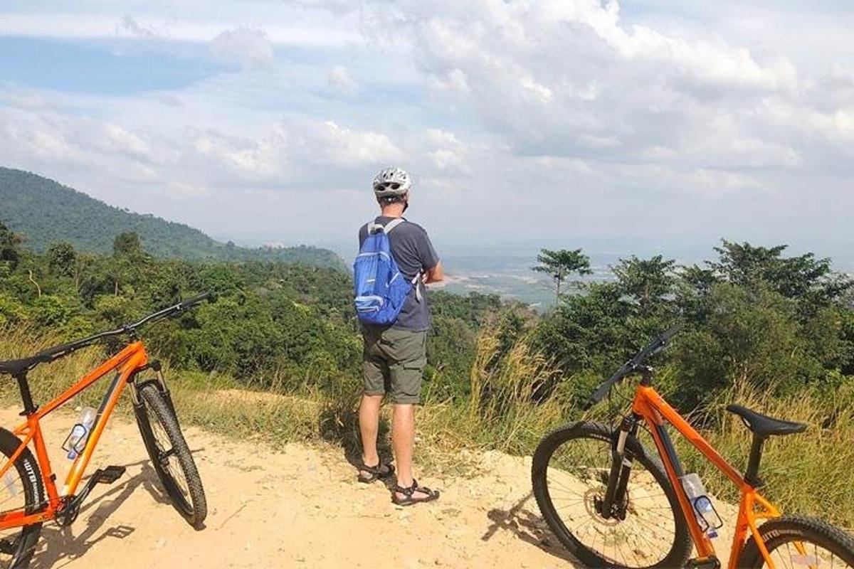 un bărbat care stă pe un drum de pământ cu două biciclete