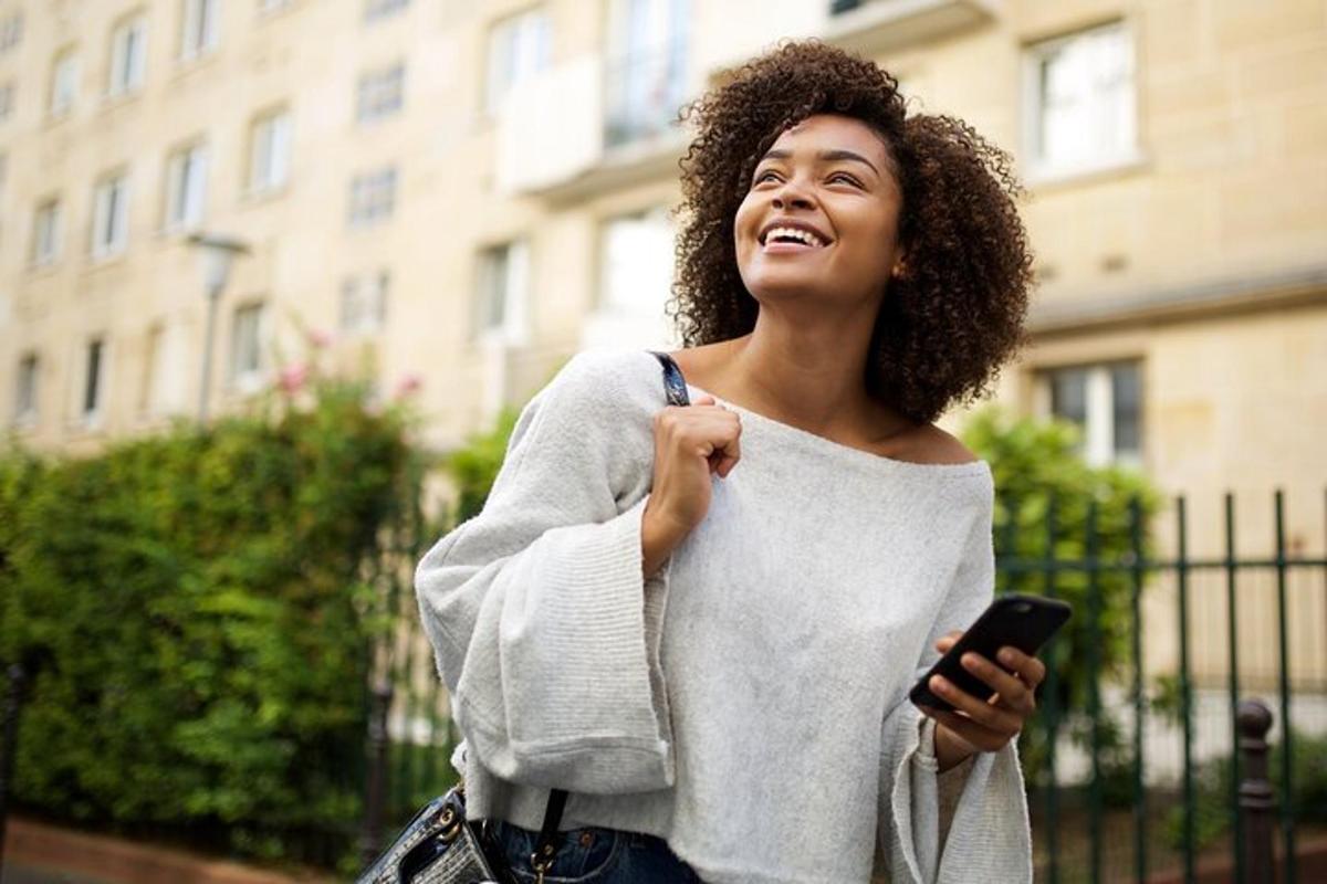 žena se usmívá a drží mobilní telefon