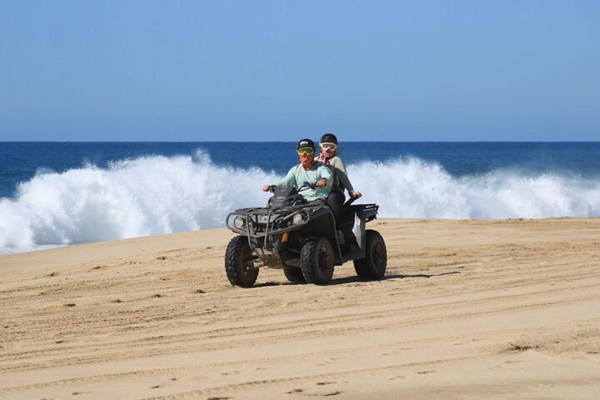 to personer kører på en quad bike på stranden