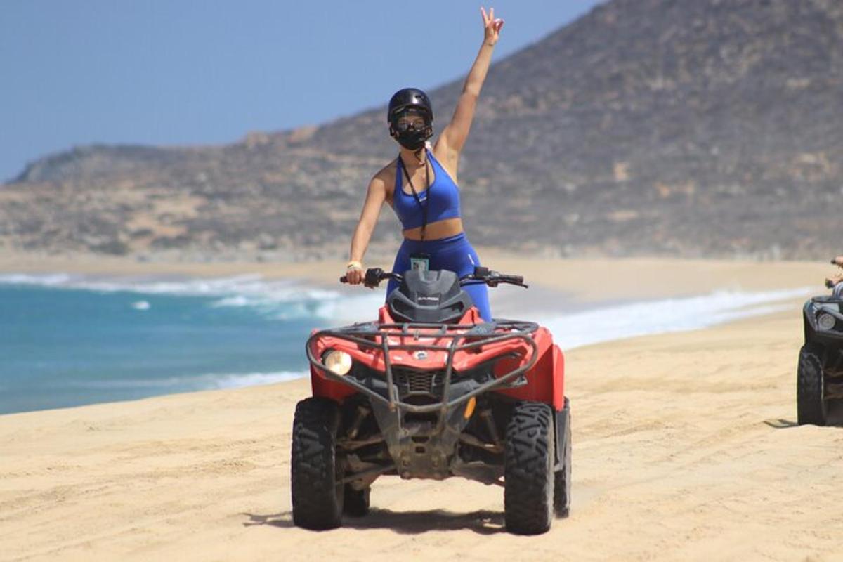 una donna in sella a un quad sulla spiaggia