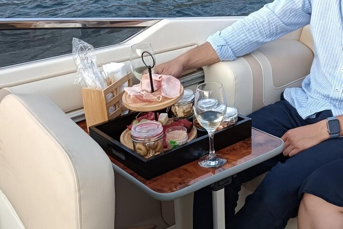 una persona seduta su una barca con un vassoio di cibo e vino