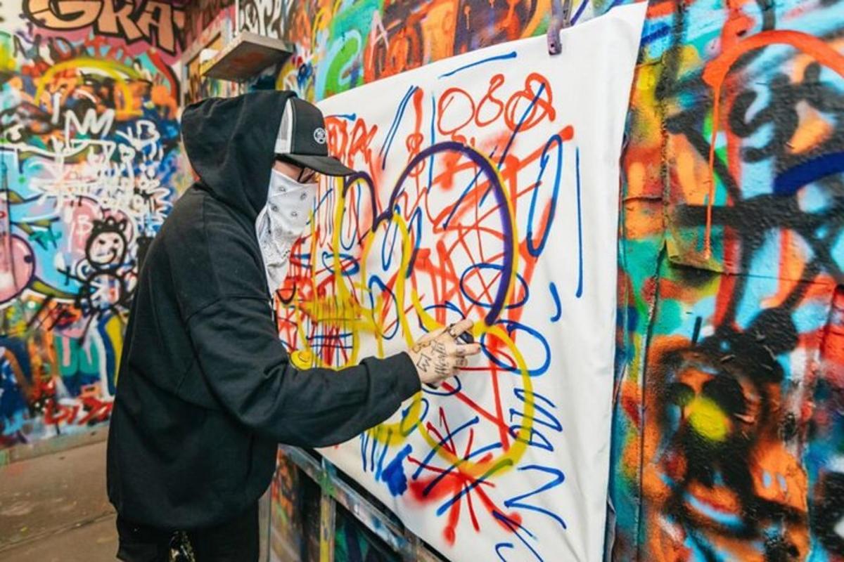 a man painting a wall with graffiti on it