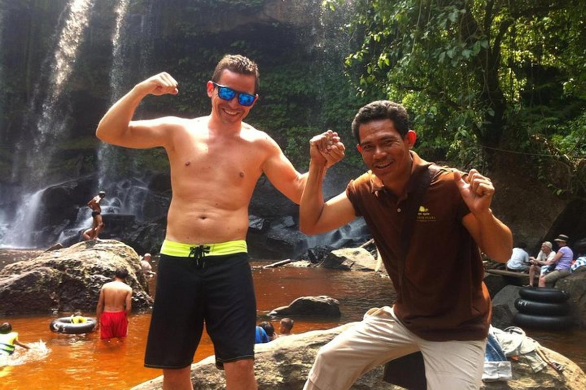 two men standing in front of a waterfall