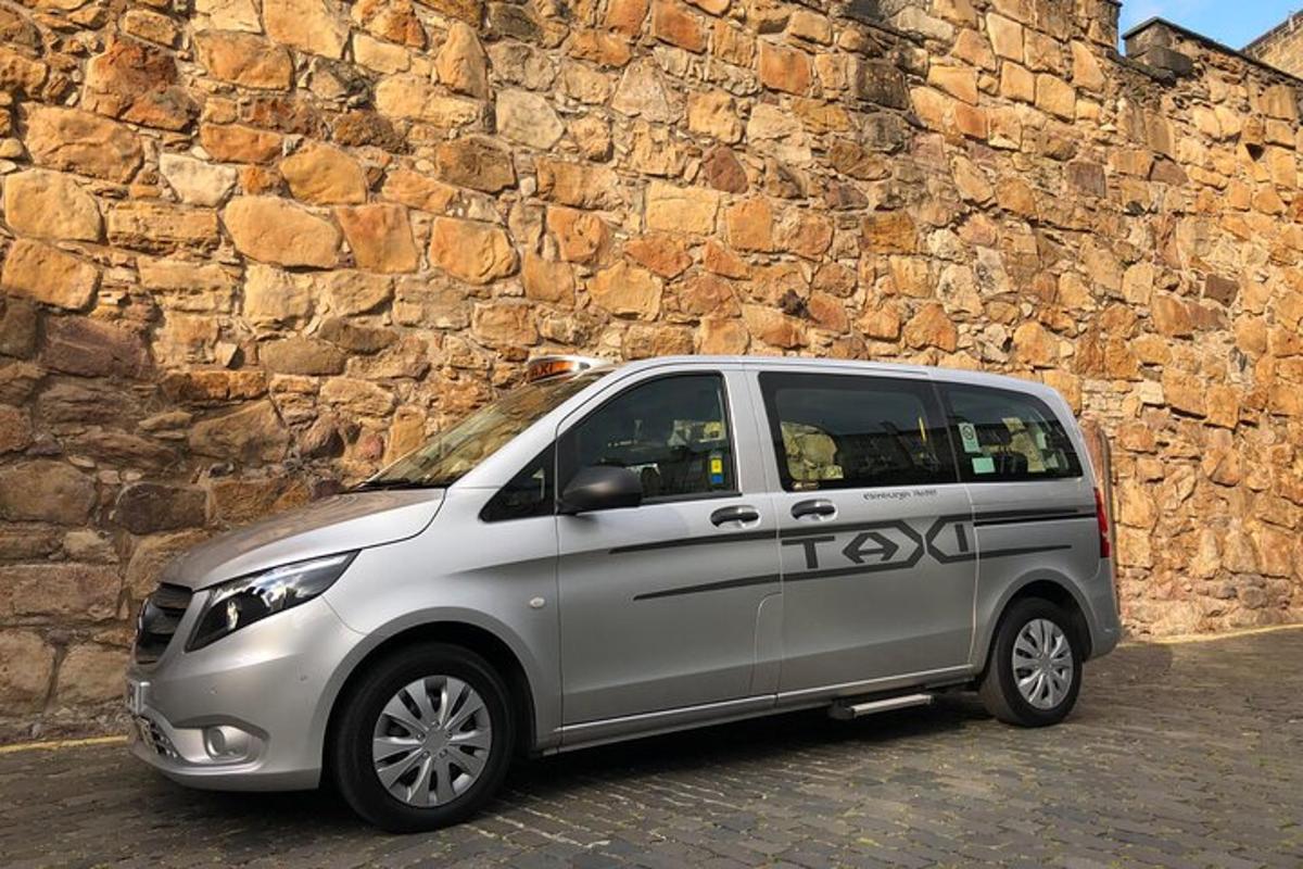 Una camioneta plateada estacionada junto a un muro de piedra