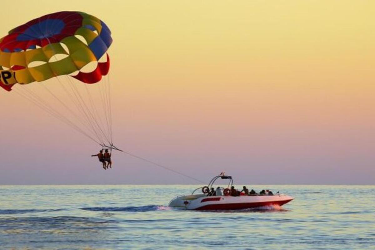 een groep mensen op een boot in het water met een parachute