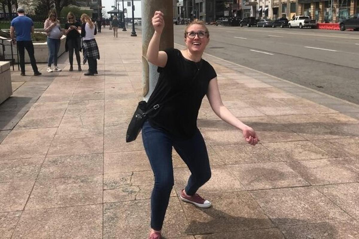 žena stojící na chodníku s rukou opřenou o tyč