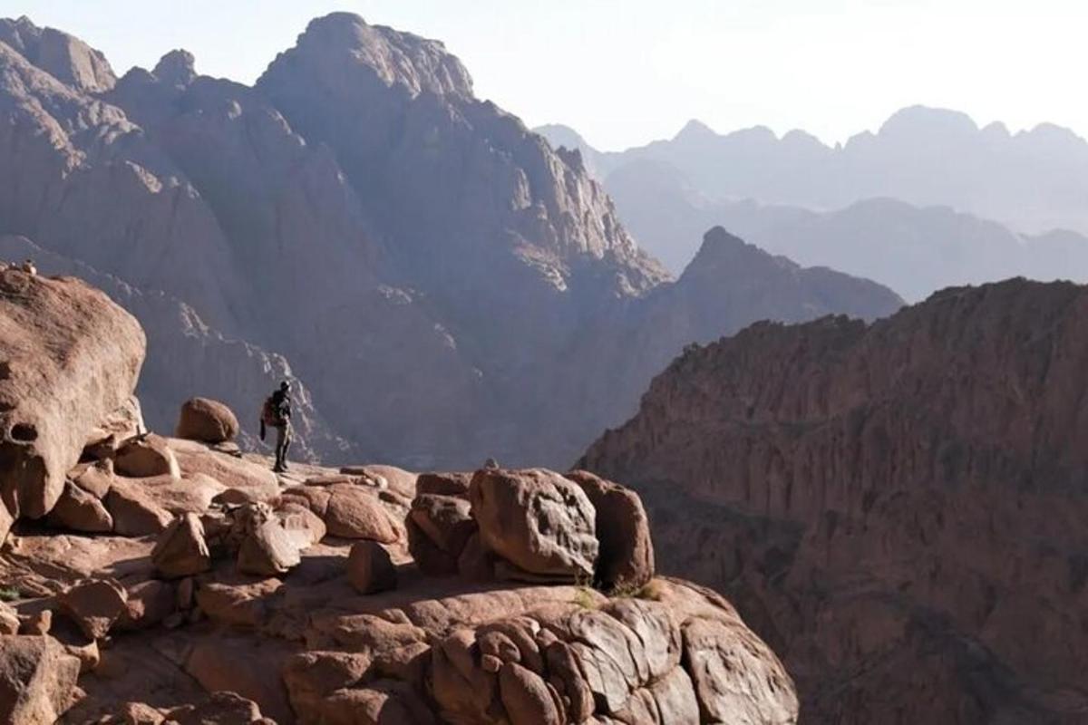 una persona in piedi sulla cima di una montagna rocciosa