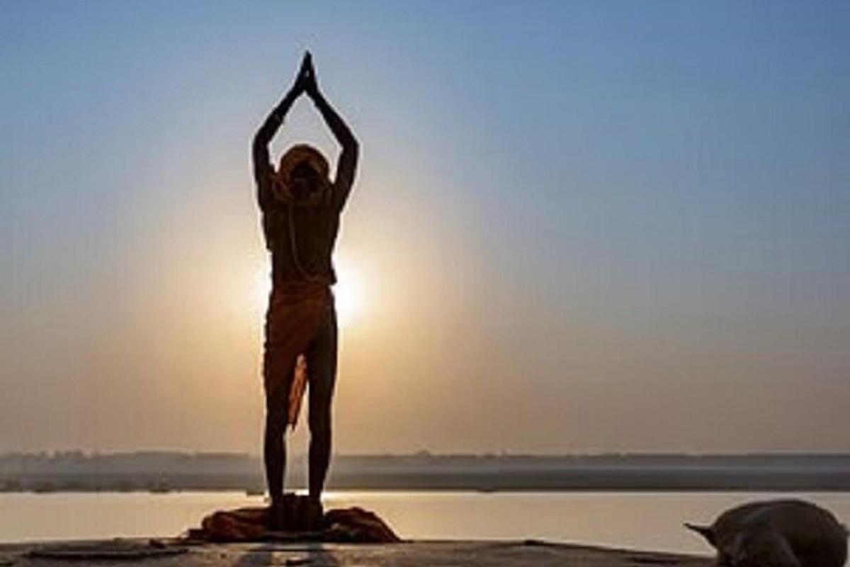 en person som gjør yoga på stranden ved solnedgang