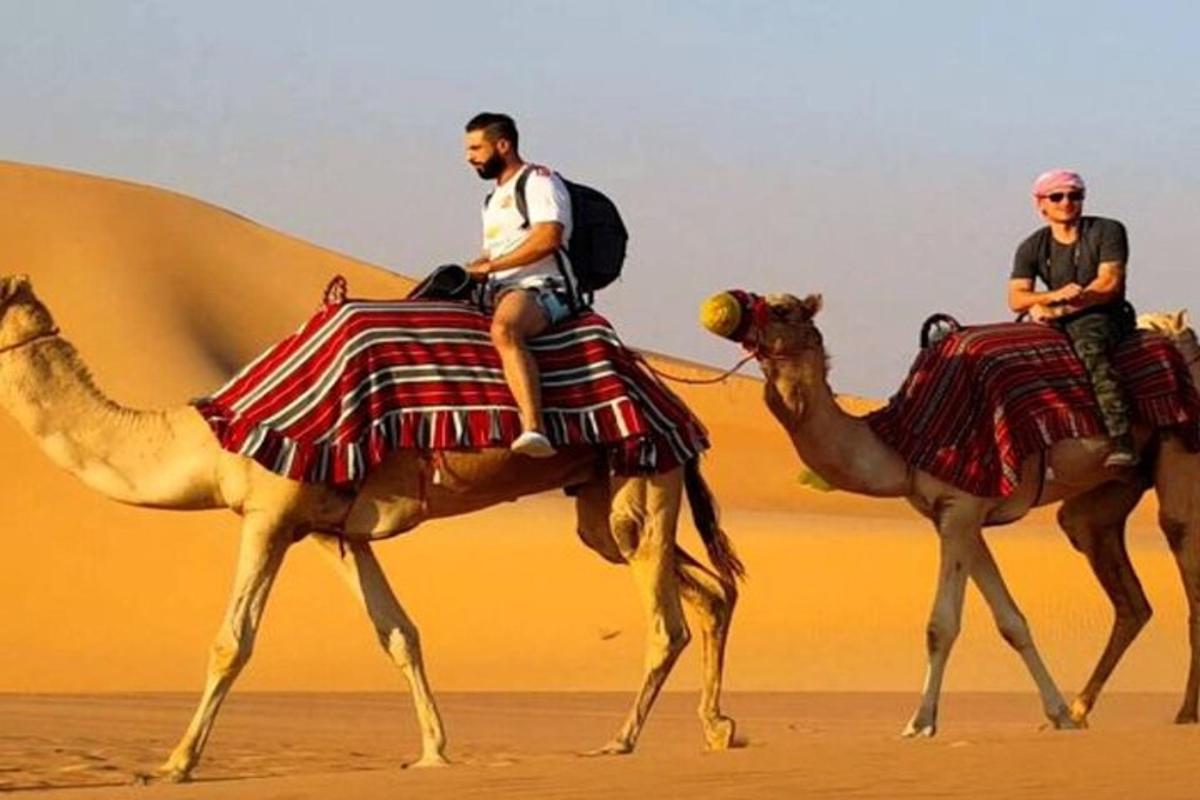 due uomini a cavallo di cammelli nel deserto