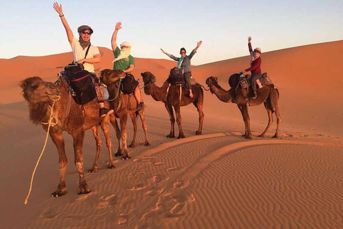 un gruppo di persone a cavallo di cammelli nel deserto