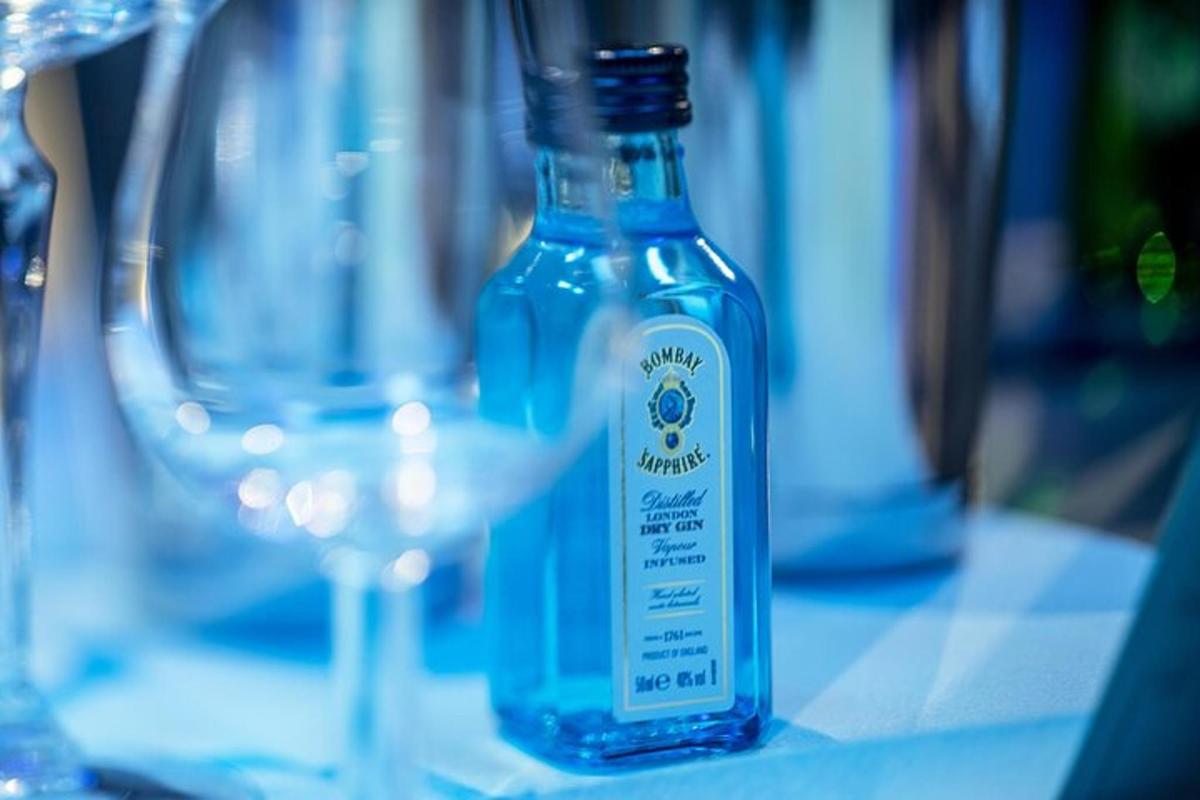 Una botella azul sobre una mesa con un vaso.