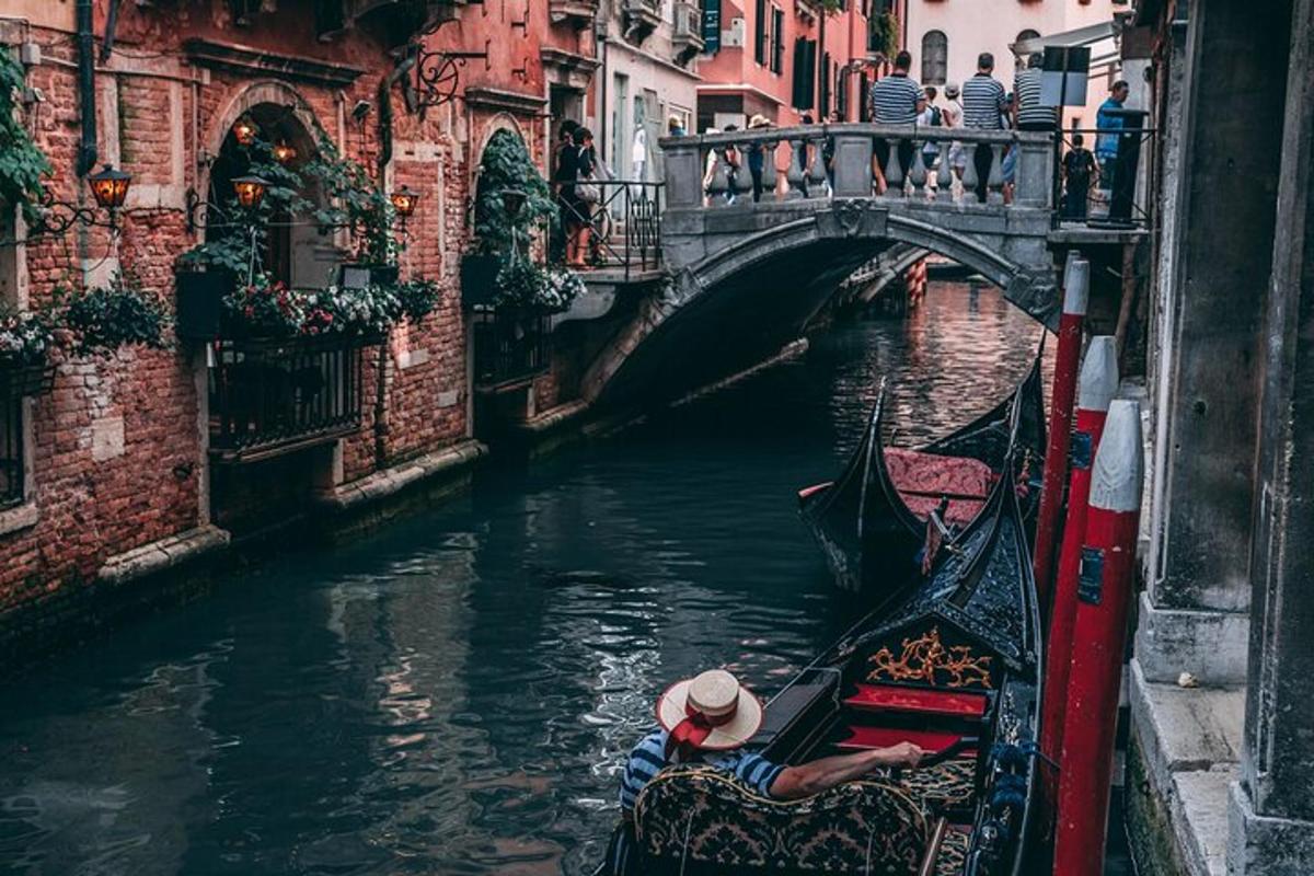 seseorang yang menaiki gondola menuruni terusan dengan jambatan