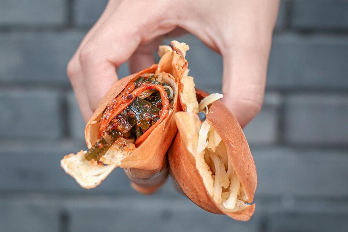 a hand holding a hot dog in a bun