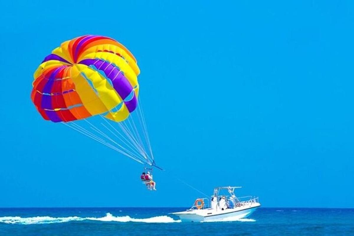 a person riding a parachute over the ocean with a boat