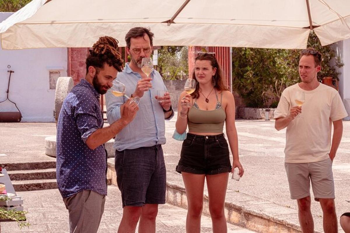 a group of people standing under an umbrella drinking wine
